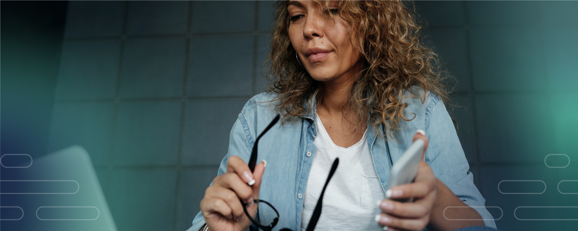 Woman looking at laptop, holding phone